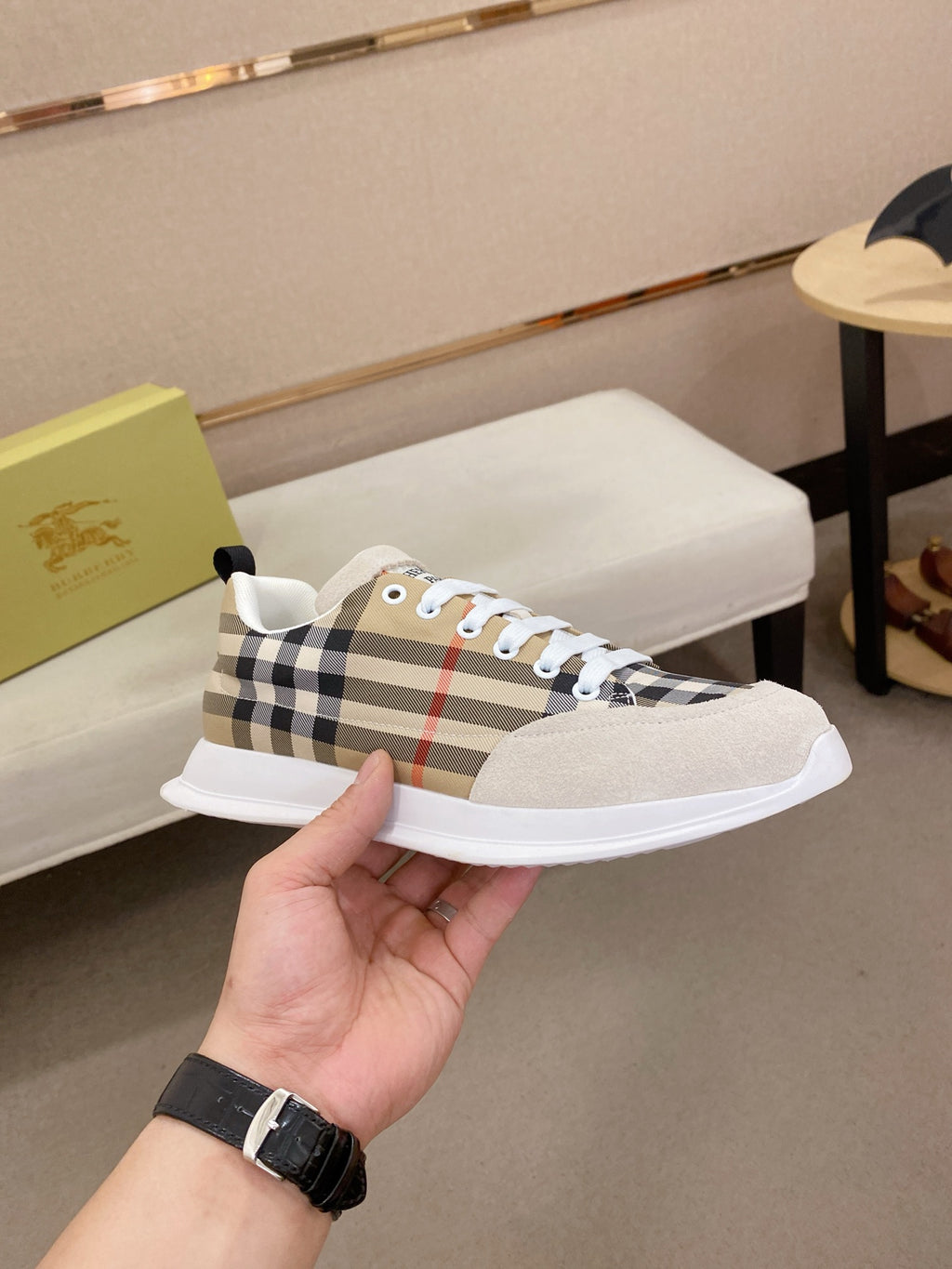Plaid canvas lace-up sneaker with white sole and light beige toe, held in hand.