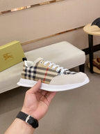Plaid canvas lace-up sneaker with white sole and light beige toe, held in hand.