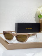 Balenciaga sunglasses, light beige frame, gold B bar detail, amber-tinted lenses