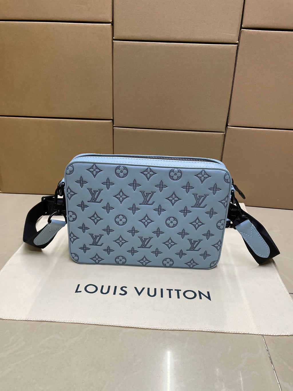 Light blue monogram crossbody bag with zipper closure and wide side panels