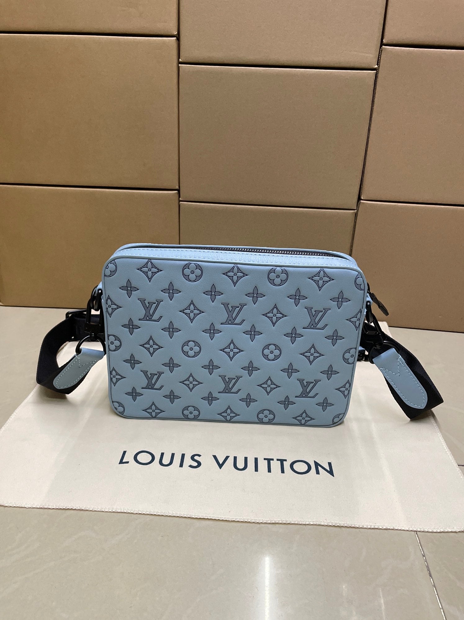 Light blue monogram crossbody bag with adjustable strap, front view