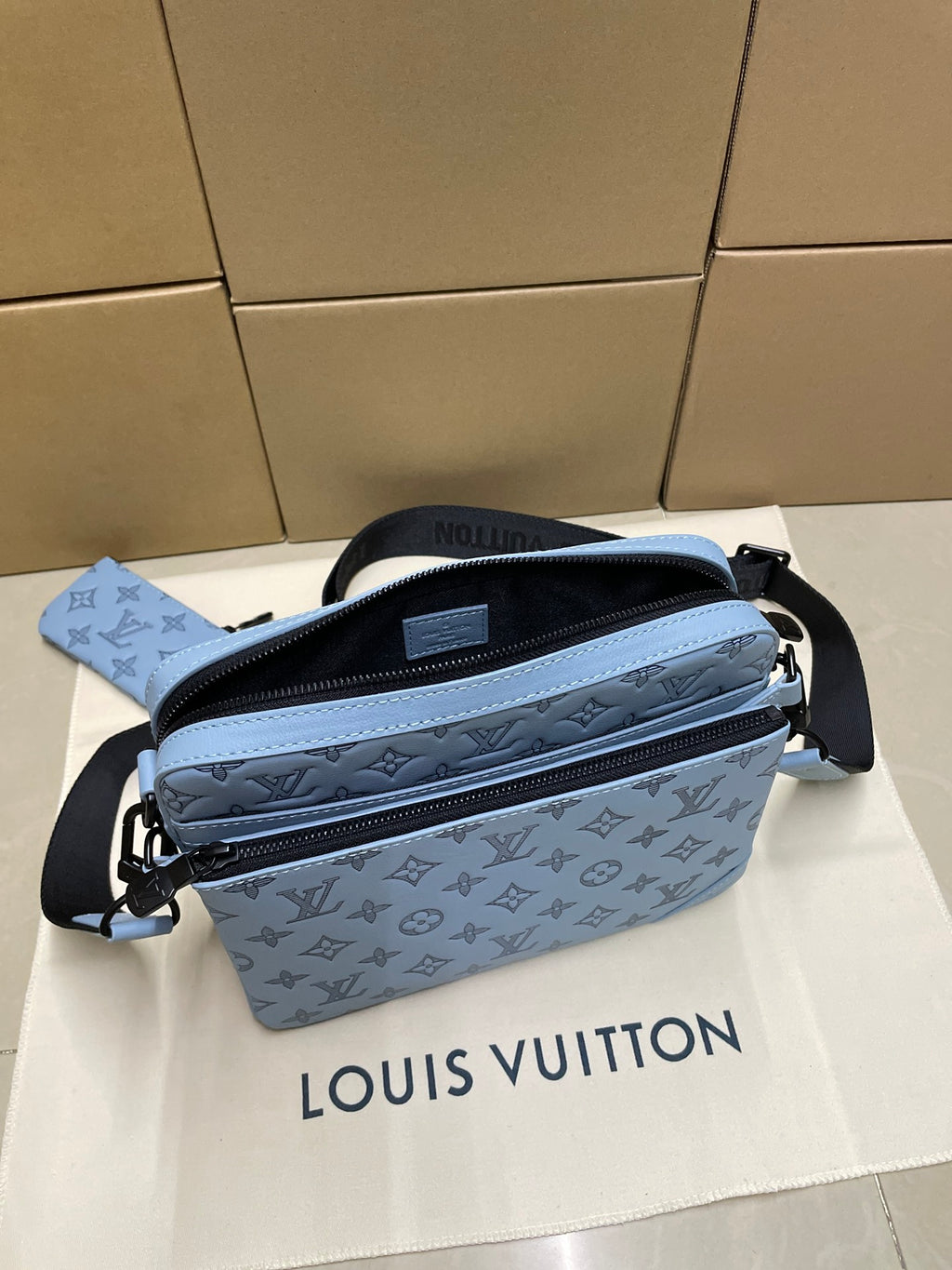 Light blue monogram crossbody bag with strap, plus small pouch beside it