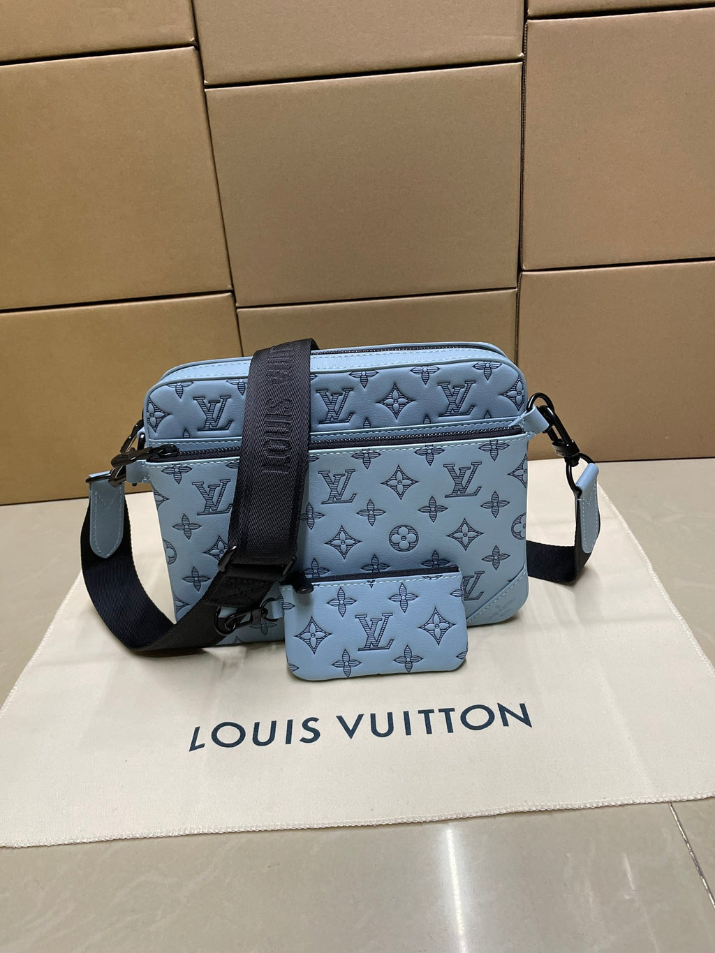 Light blue monogram crossbody bag with front flap and adjustable shoulder strap