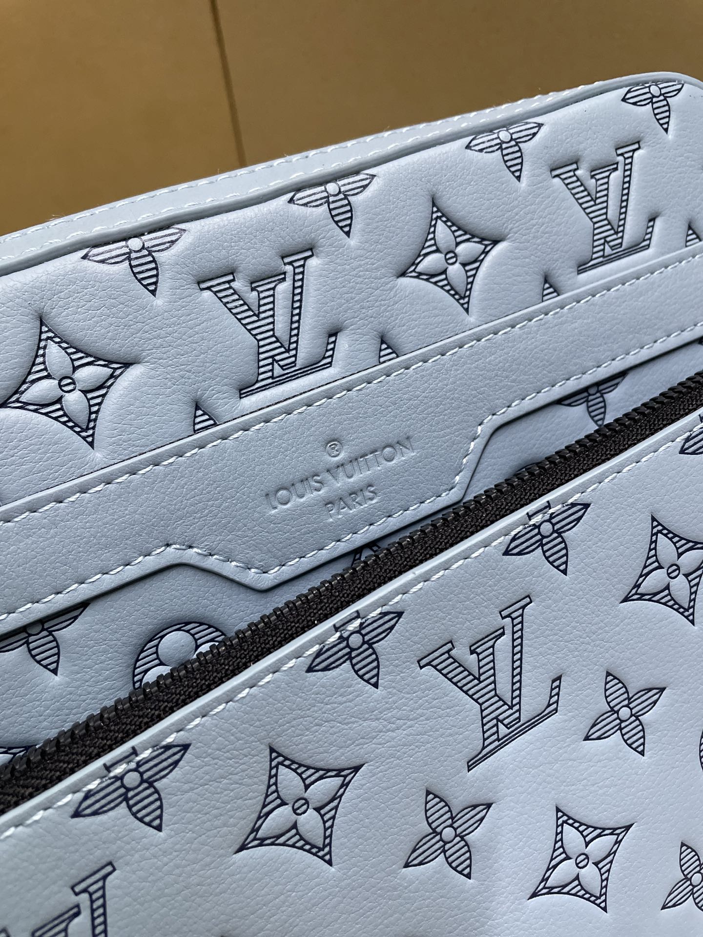 Light blue monogram crossbody bag detail with patterned leather and contrast stitching