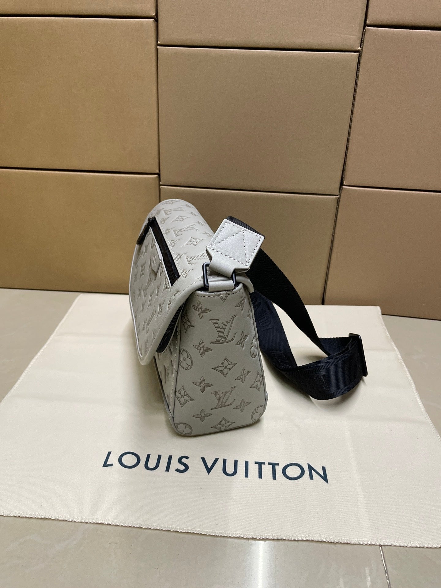 Louis Vuitton men’s crossbody bag, side view with light monogram and black shoulder strap