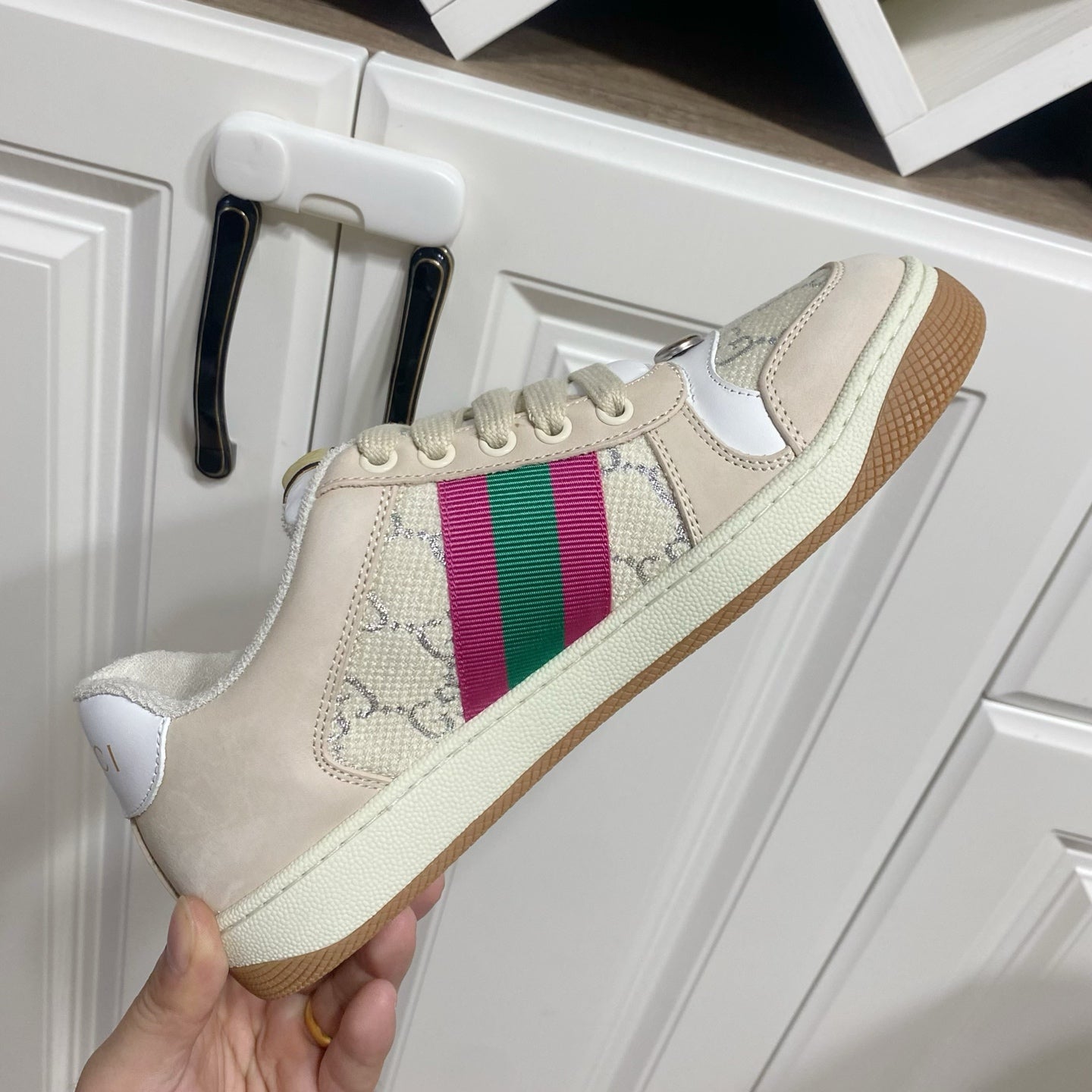 Gucci unisex lace-up sneaker on white door, beige upper with multicolor stripe