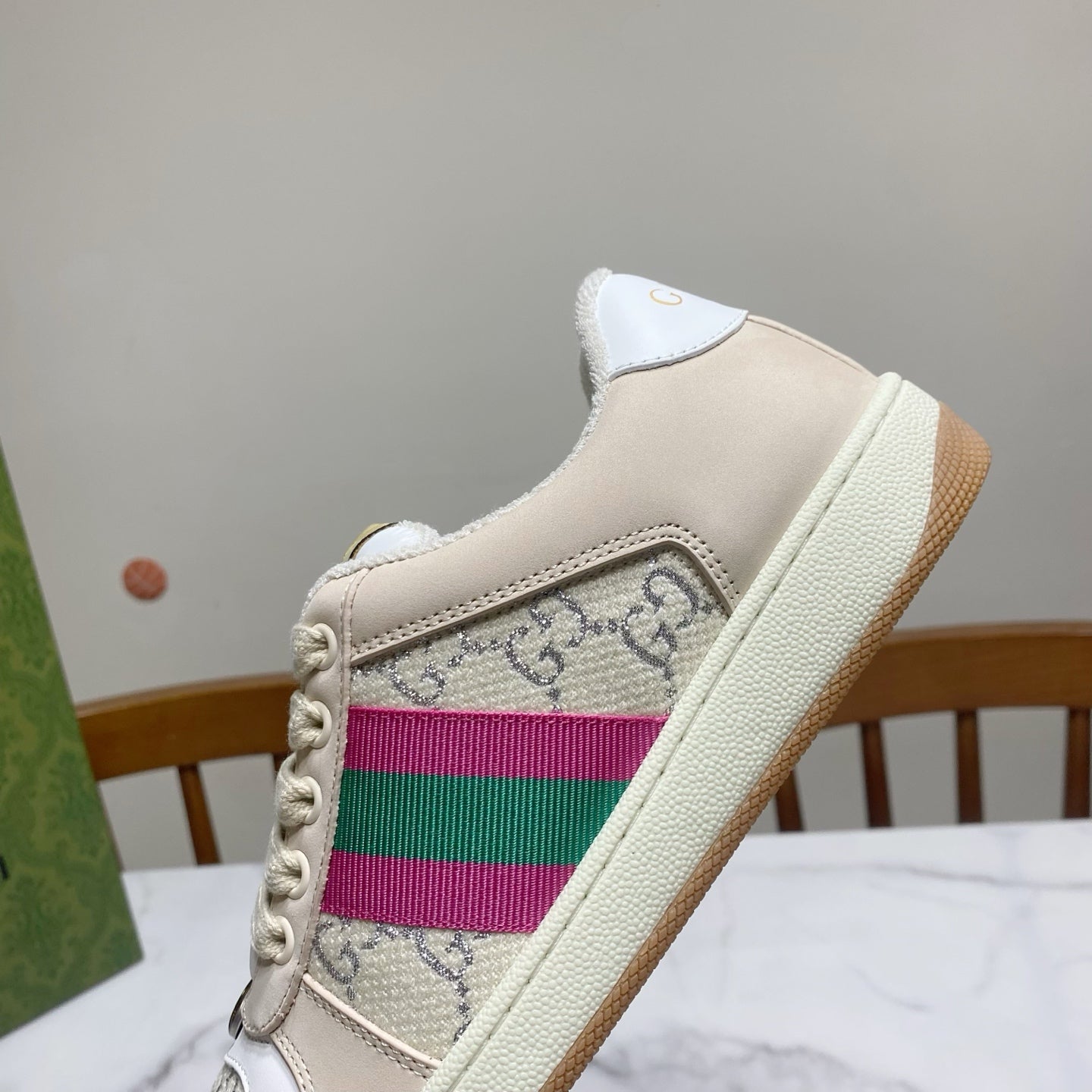 Cream Gucci unisex sneaker close-up with striped side panel and embossed logo