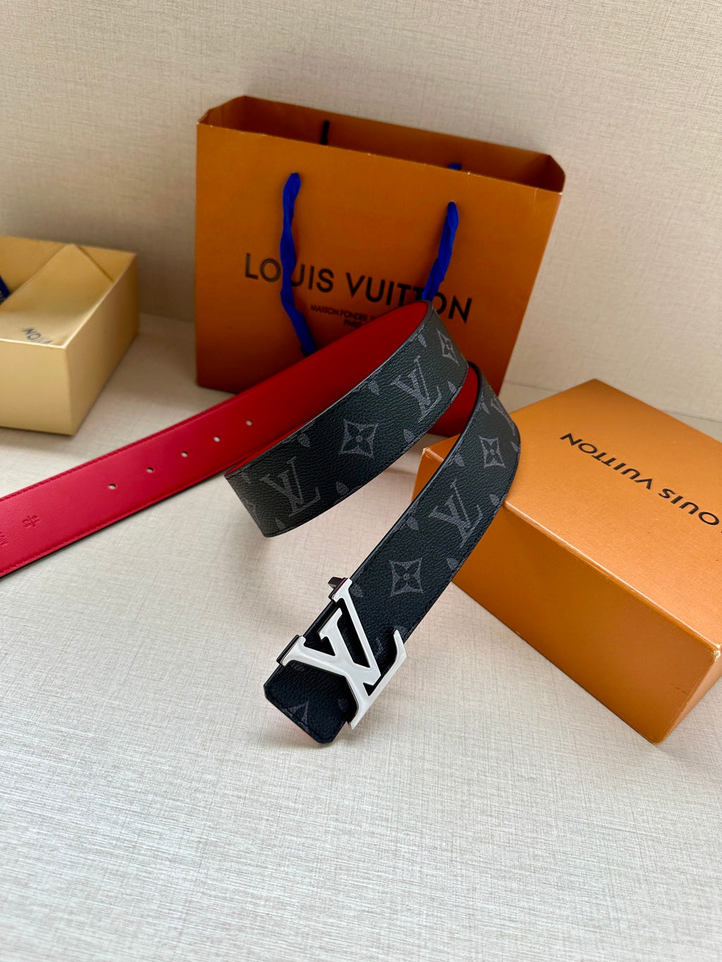 Navy monogram leather belt with gold LV buckle and red-lined strap