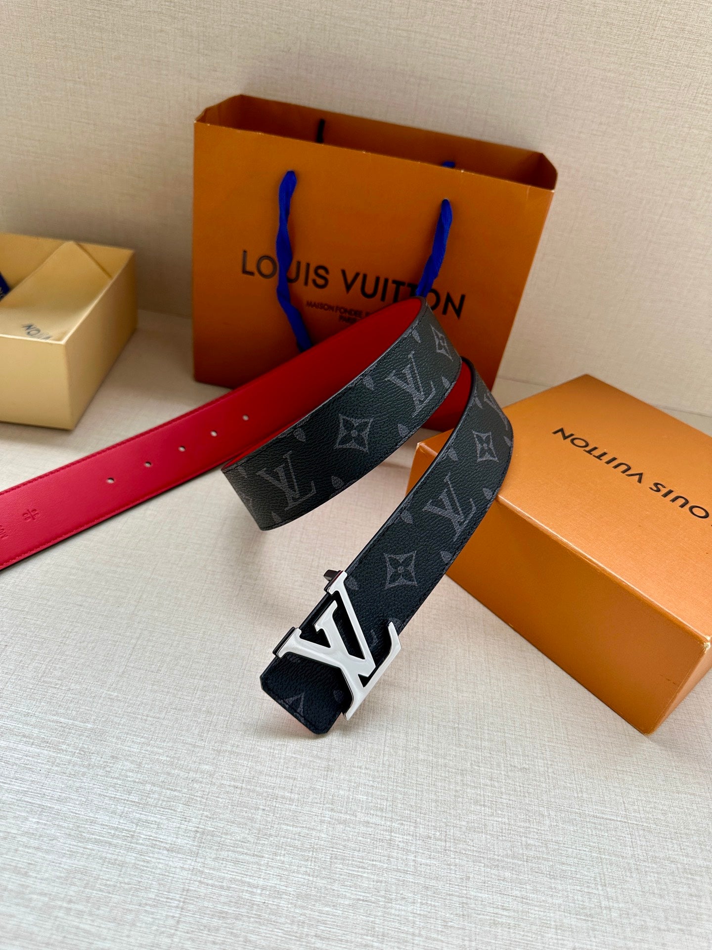 Navy monogram leather belt with gold LV buckle and red-lined strap