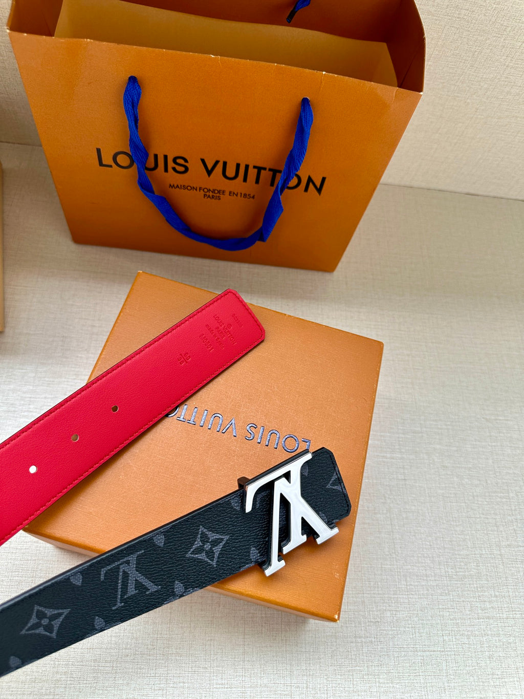 Red-tipped navy monogram belt with gold LV buckle and red underside