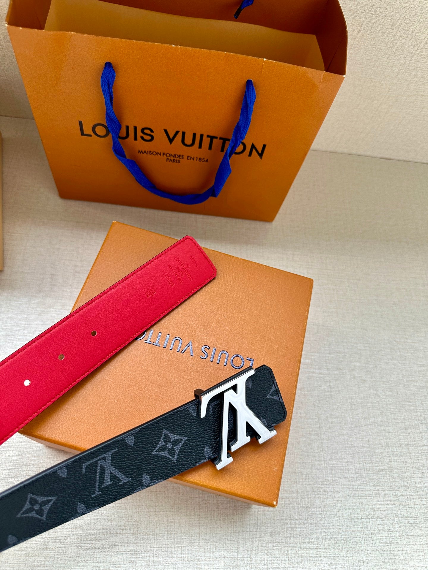 Red-tipped navy monogram belt with gold LV buckle and red underside