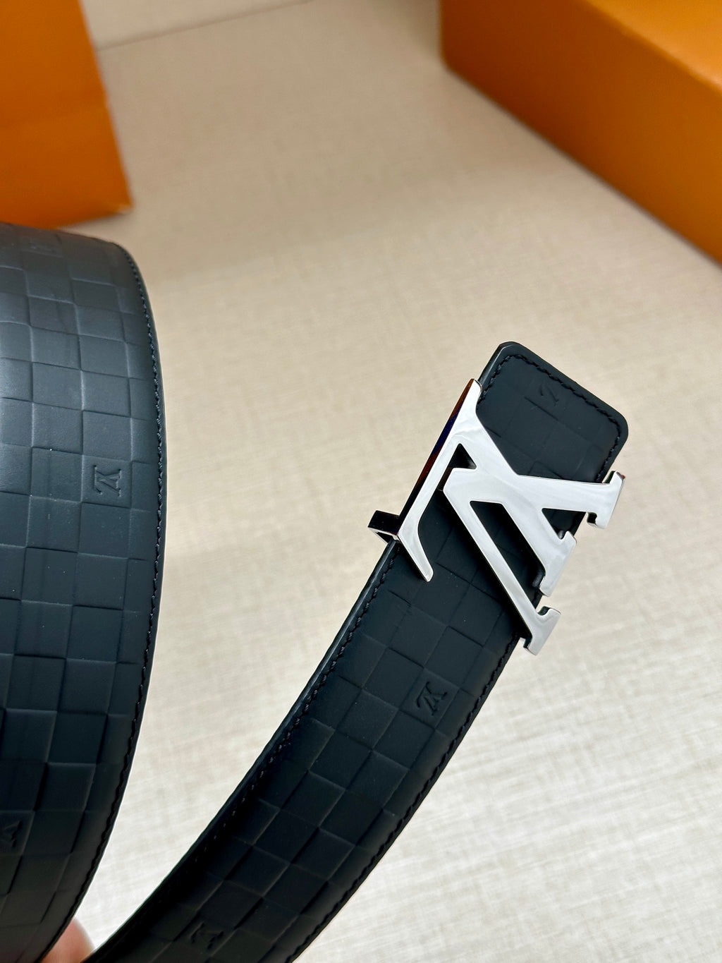 Blue embossed belt strap with silver LV buckle and adjustment holes.