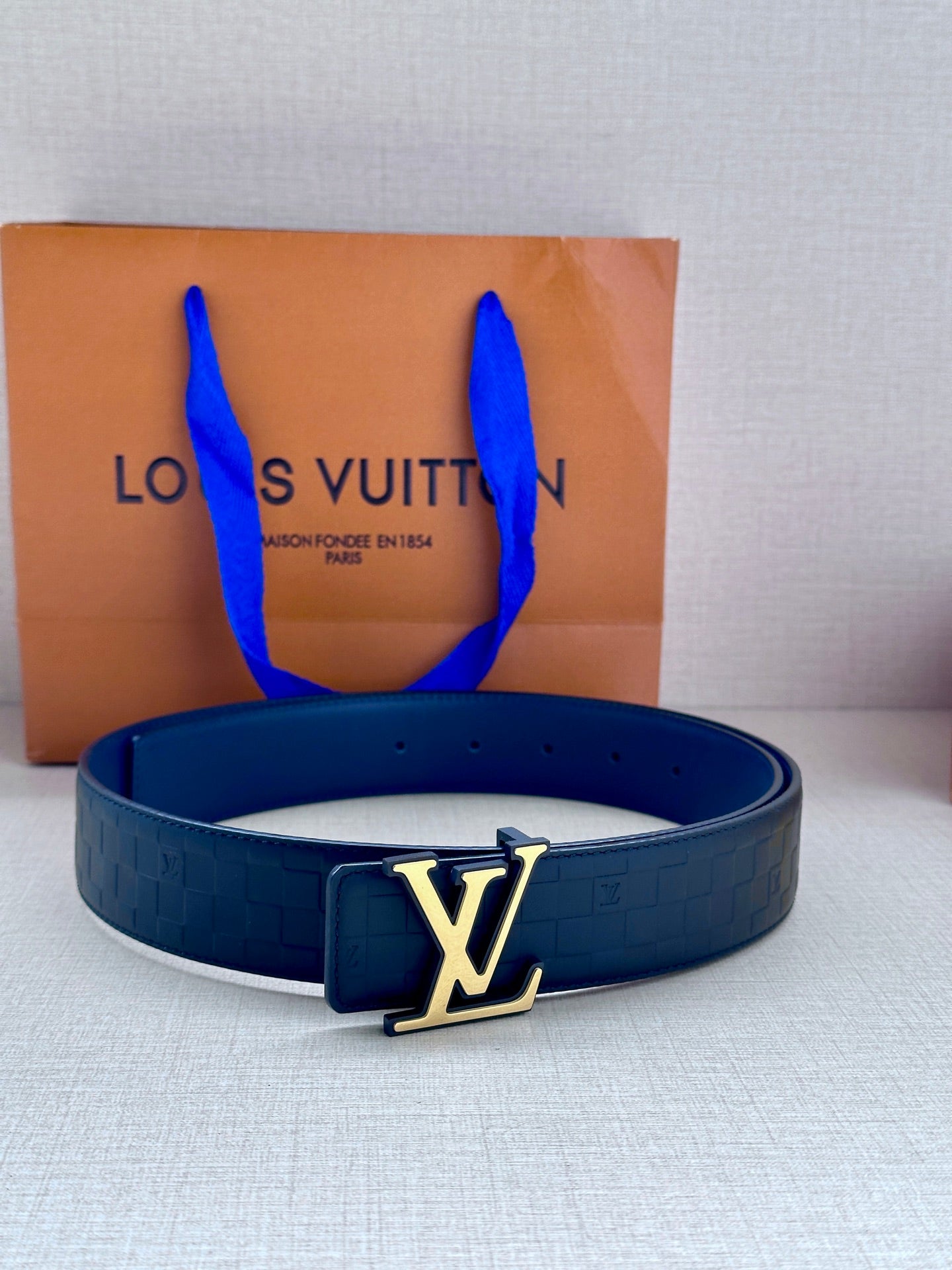 Louis Vuitton belt with dark blue embossed leather strap and gold LV buckle