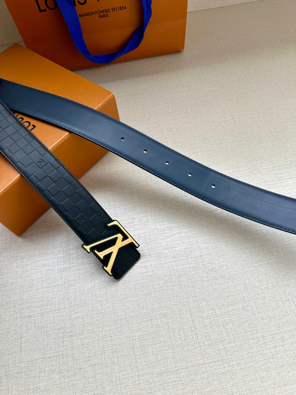 Louis Vuitton belt pair: dark blue embossed straps with gold buckle accents