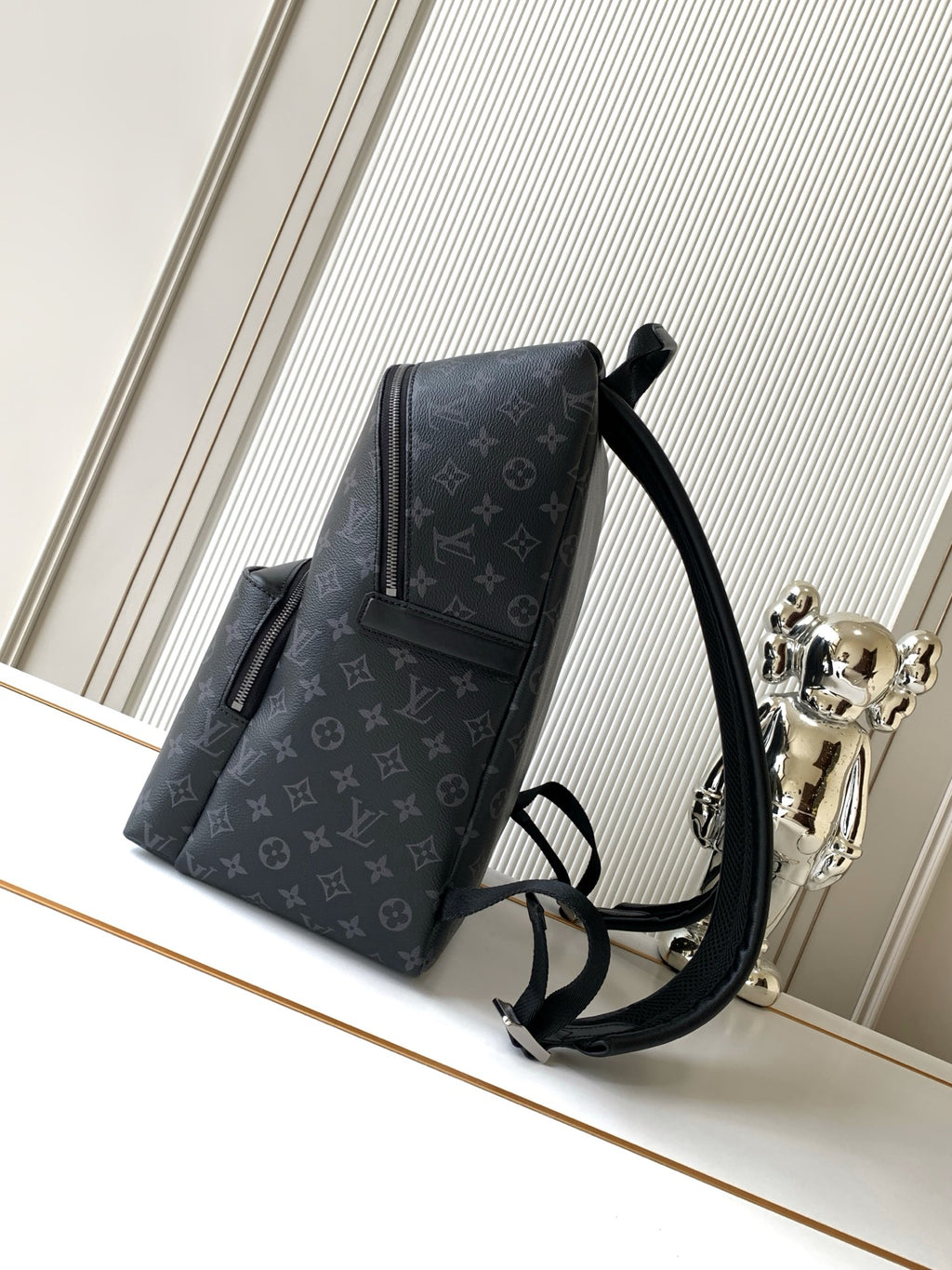 Men's designer monogram backpack shown at an angle with shoulder straps