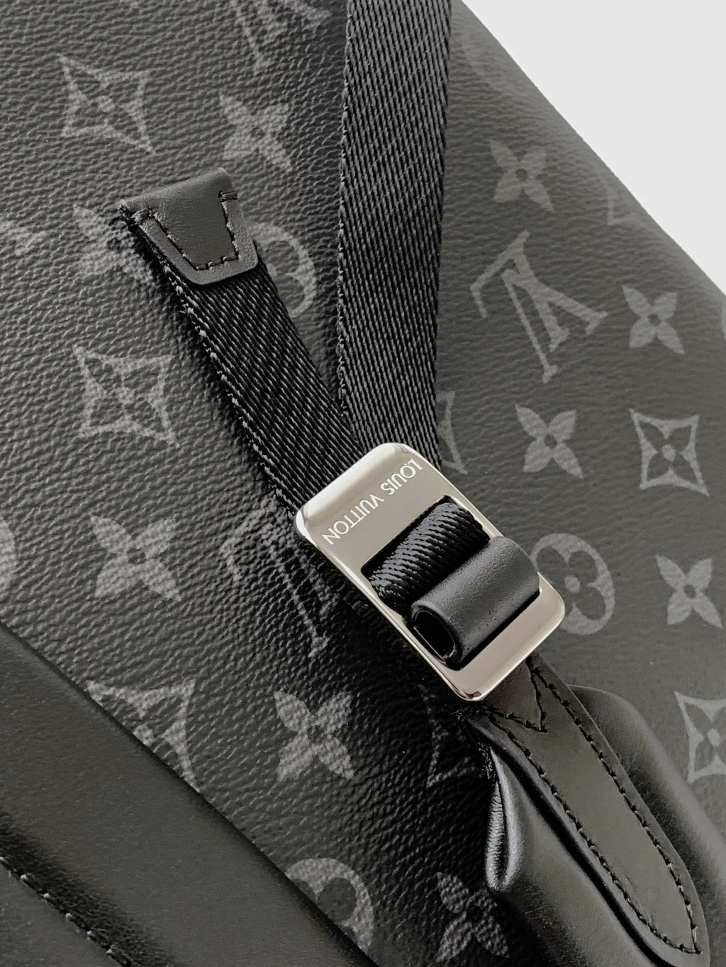 Close-up of adjustable strap and metal connector on dark monogram backpack