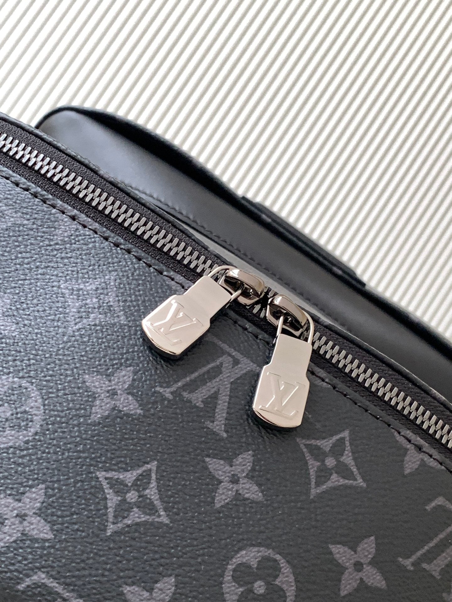 Close-up of dark monogram backpack zipper pull and metal pull tabs