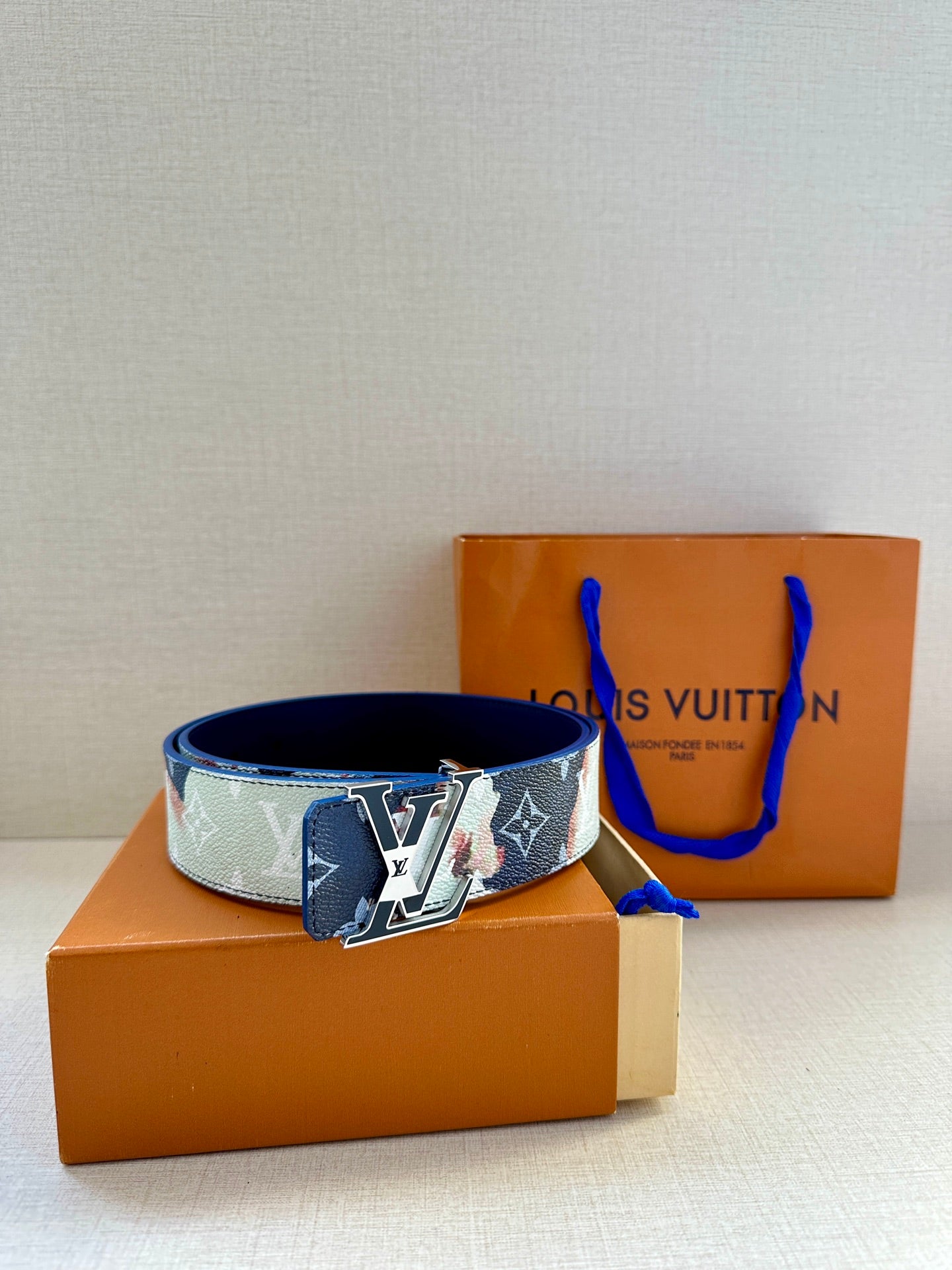 Louis Vuitton monogram belt with blue strap and silver-gold buckle center.