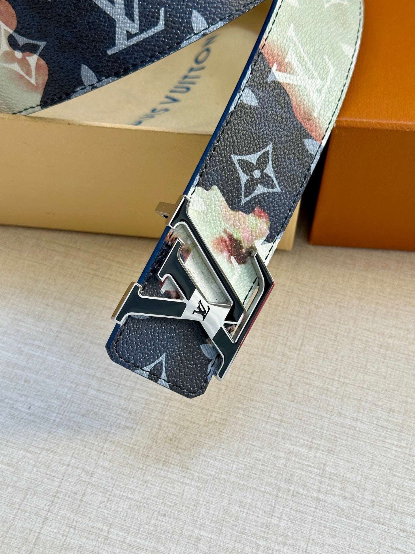 Louis Vuitton monogram belt close-up: blue strap with multicolor patches and gold buckle.