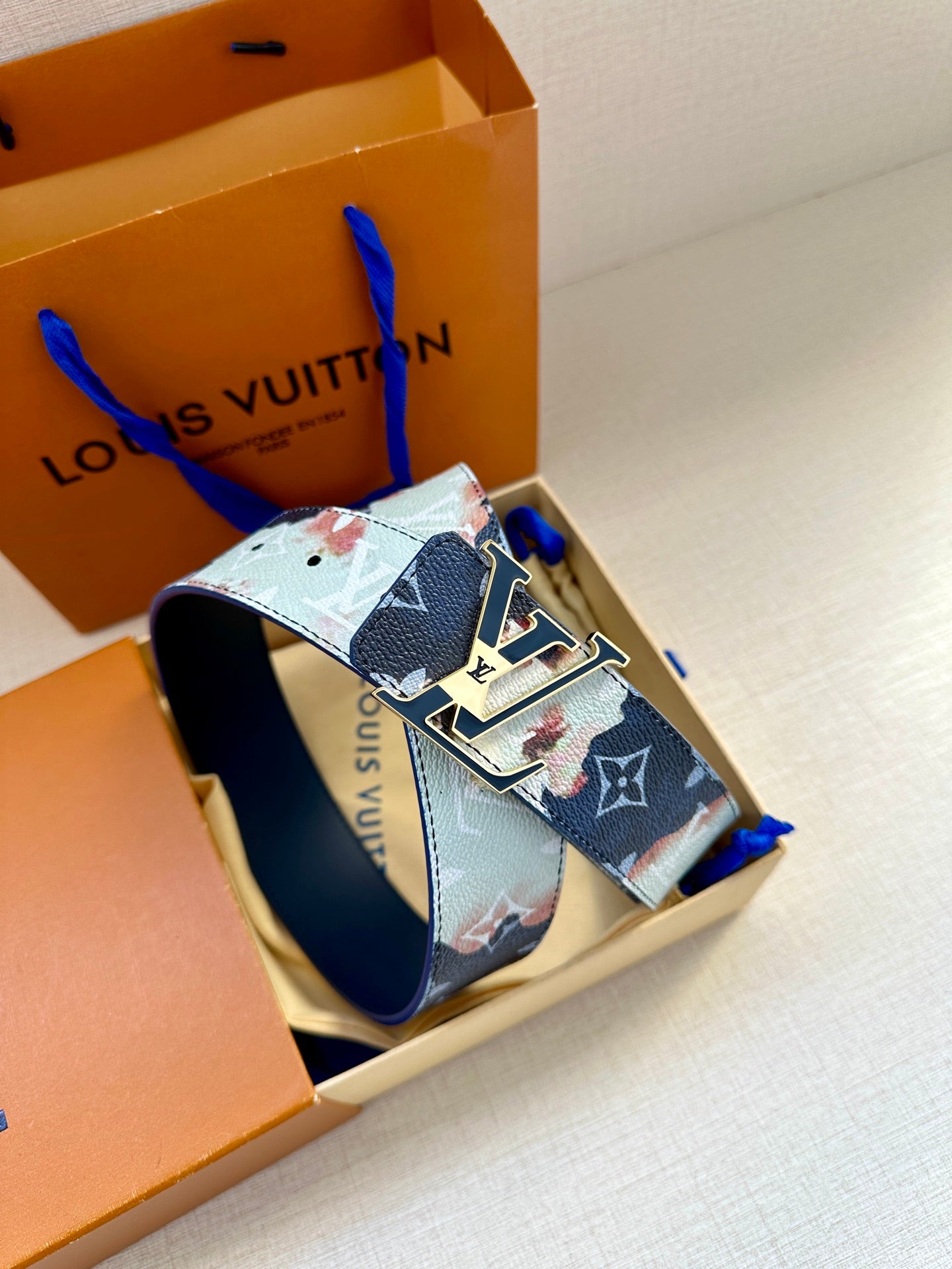 Louis Vuitton belt with blue monogram strap and gold-tone buckle with LV plates.
