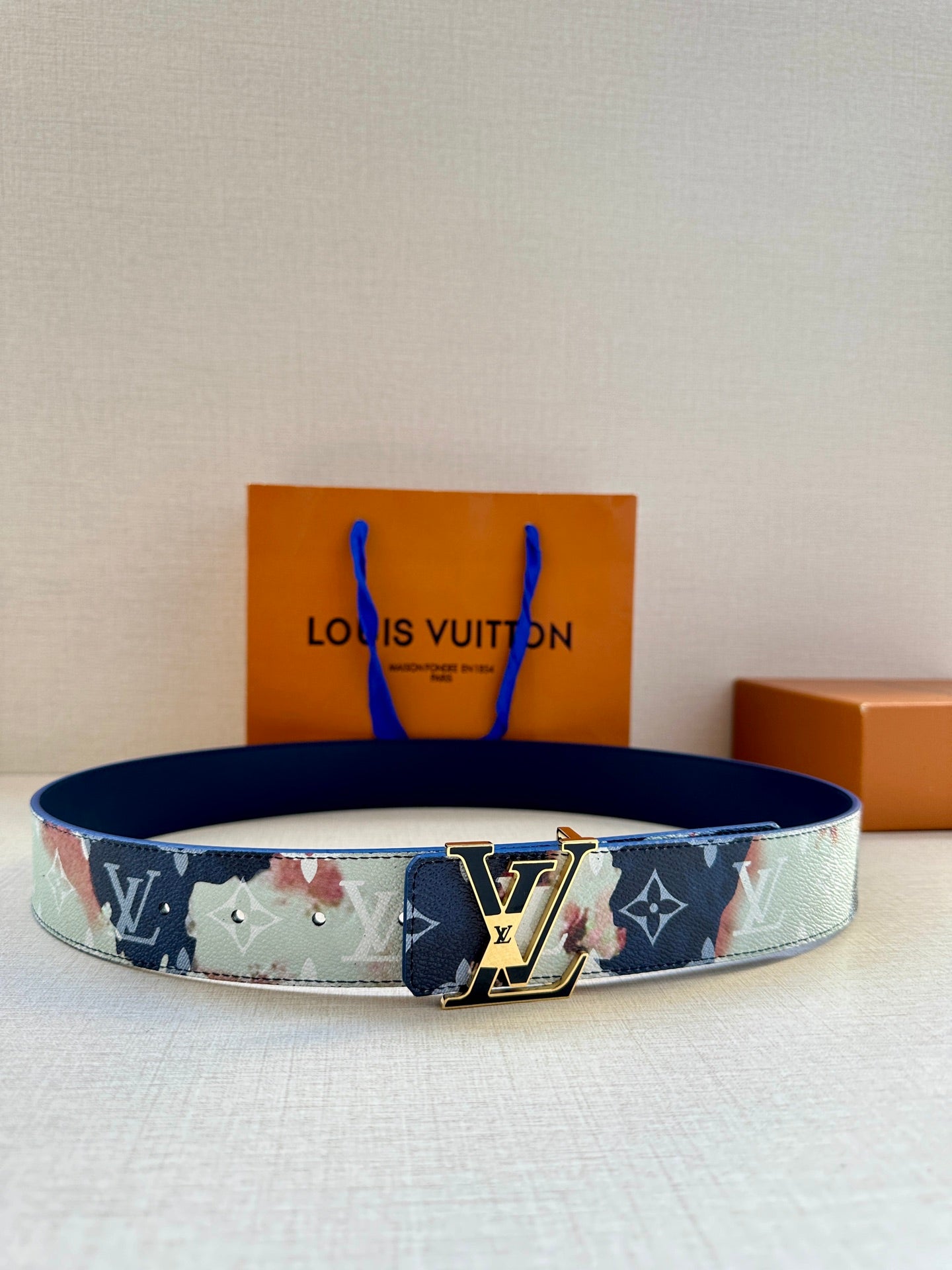 Louis Vuitton monogram belt with dark blue strap and gold-tone buckle.