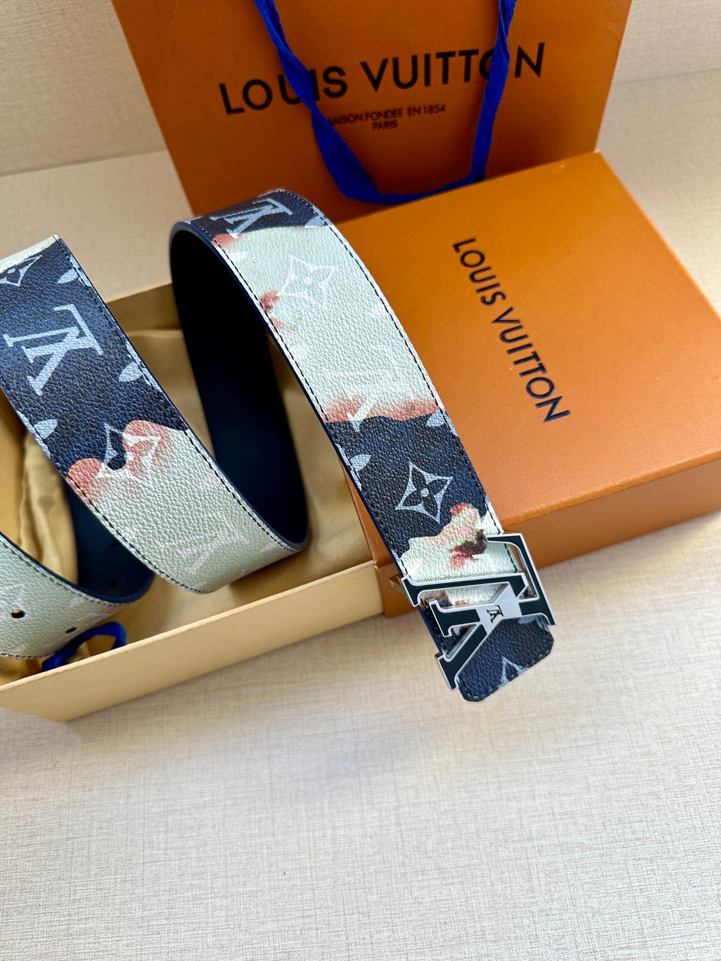 Louis Vuitton belt with blue-and-white monogram strap and silver-and-gold buckle.