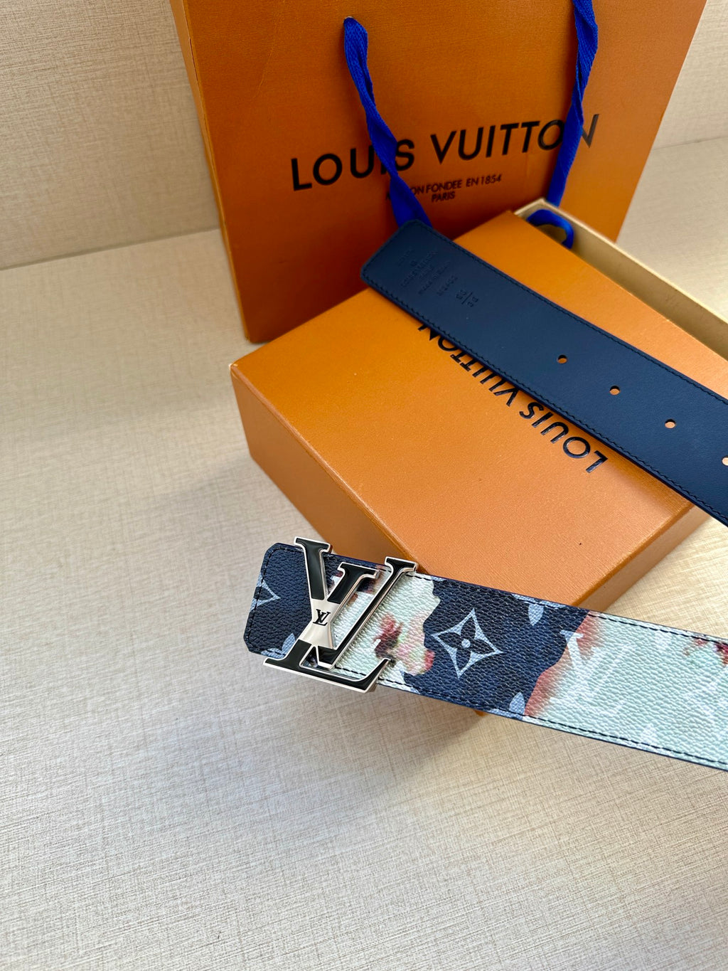 Louis Vuitton belt with blue monogram strap and gold-tone buckle on metal plates.
