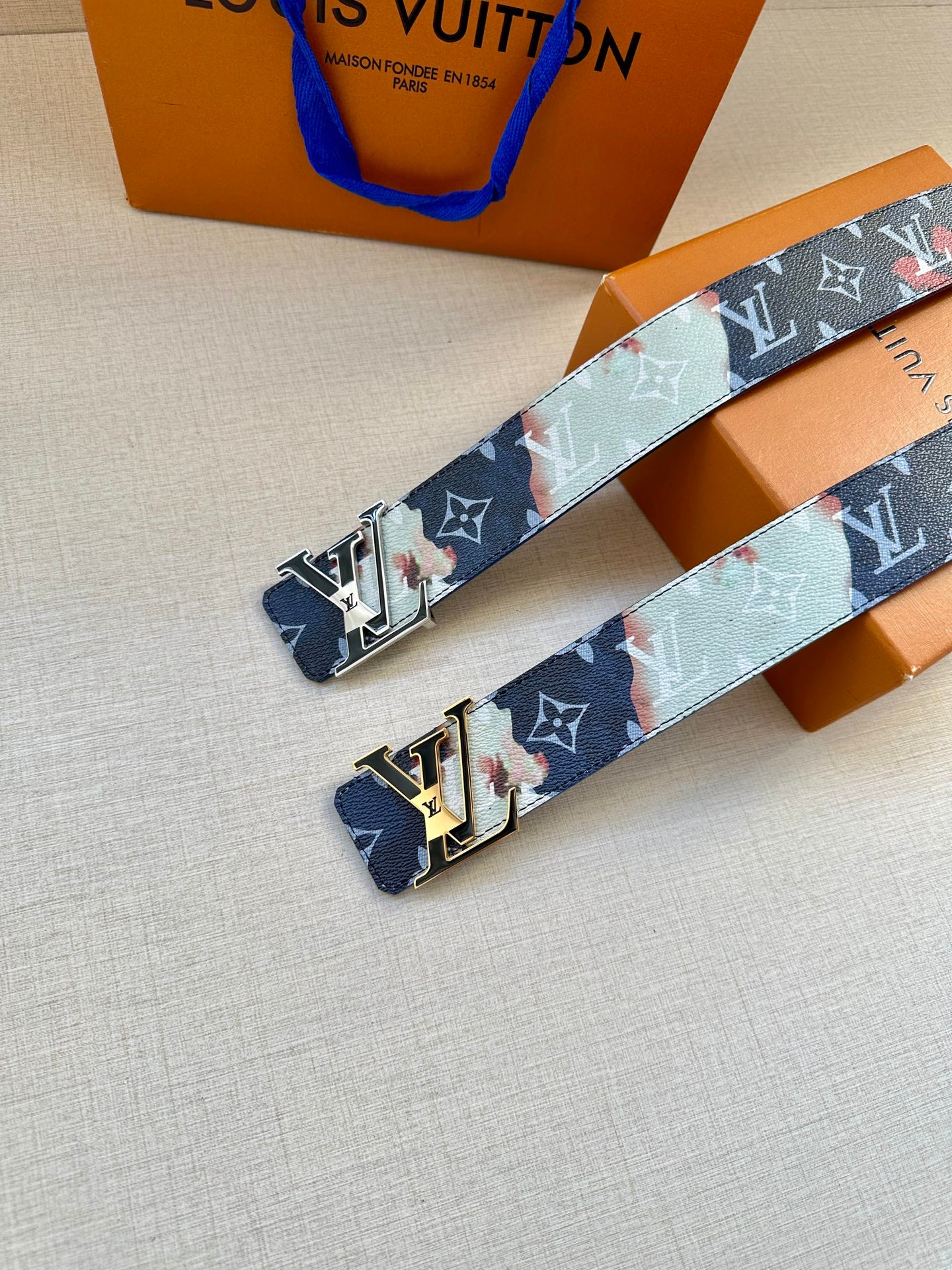 Set of Louis Vuitton monogram belts with blue straps and silver-gold buckle plates.