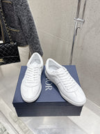 White Dior unisex sneakers, angled front view with Dior logo on sides