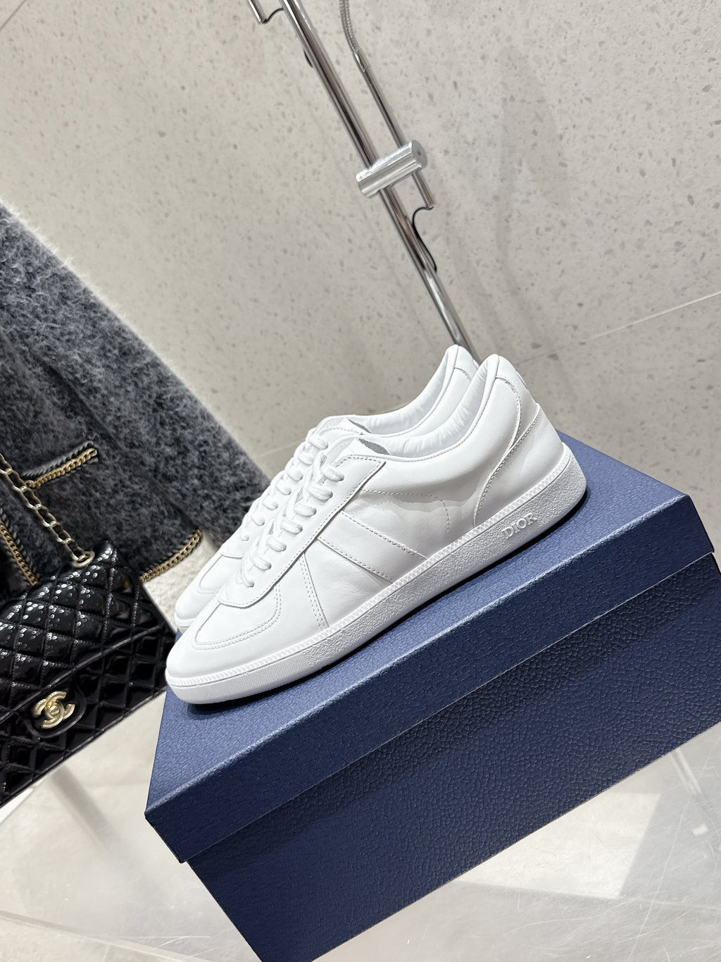 White Dior unisex sneakers, side angle on blue box, lace-up design