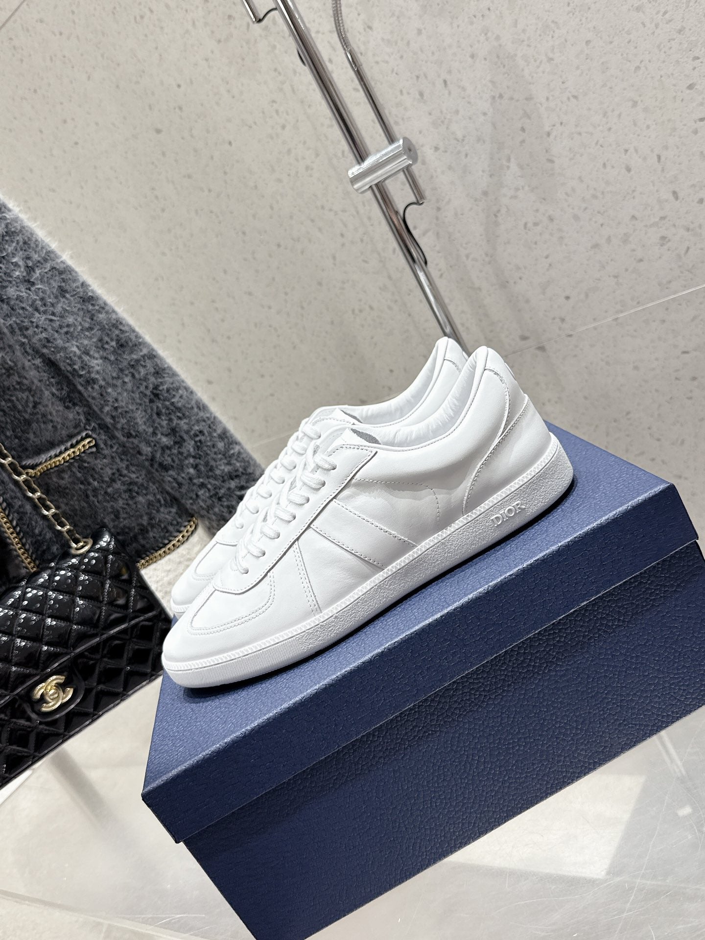 White Dior unisex sneakers, side angle on blue box, lace-up design