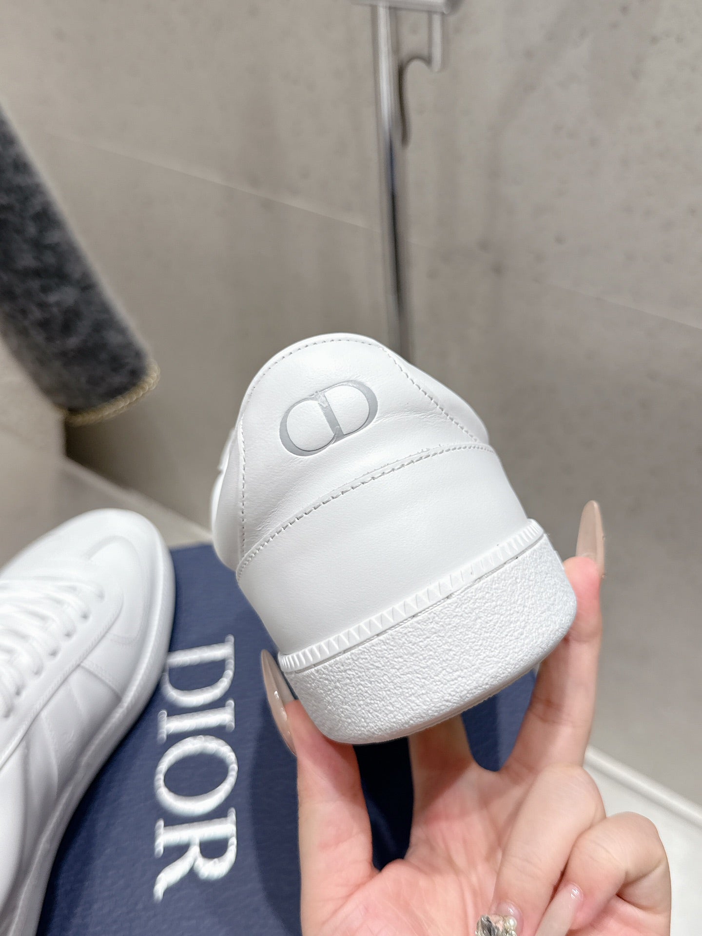 White Dior unisex sneaker heel close-up, embossed Dior logo on back