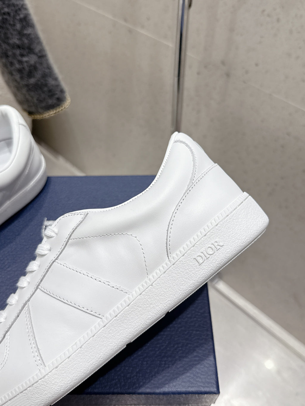 White Dior unisex sneaker on blue box, side panel and stitched trim