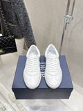 White Dior unisex sneakers on blue box, lace-up with stitched panels