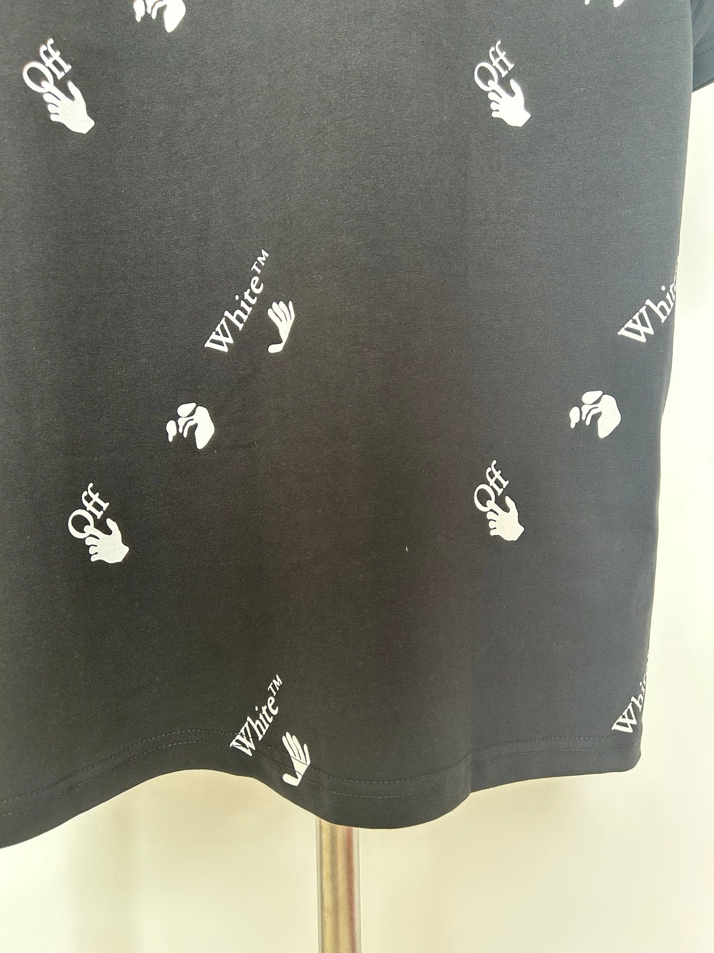 Black T-shirt lower back close-up with scattered white hand logos