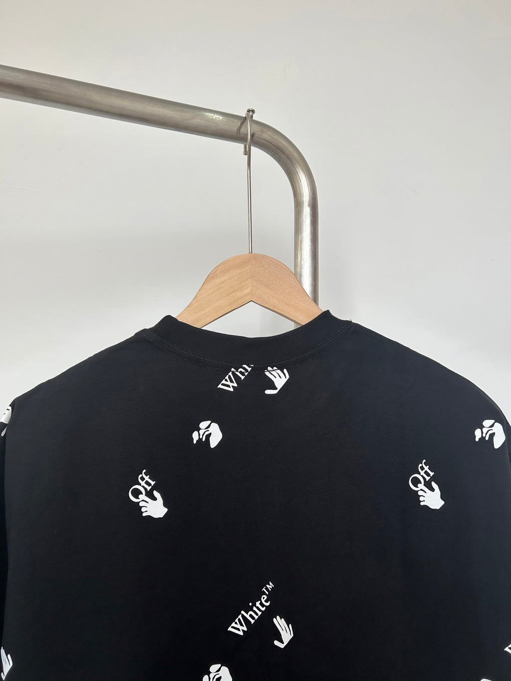 Black T-shirt back view with white hand logos across shoulders