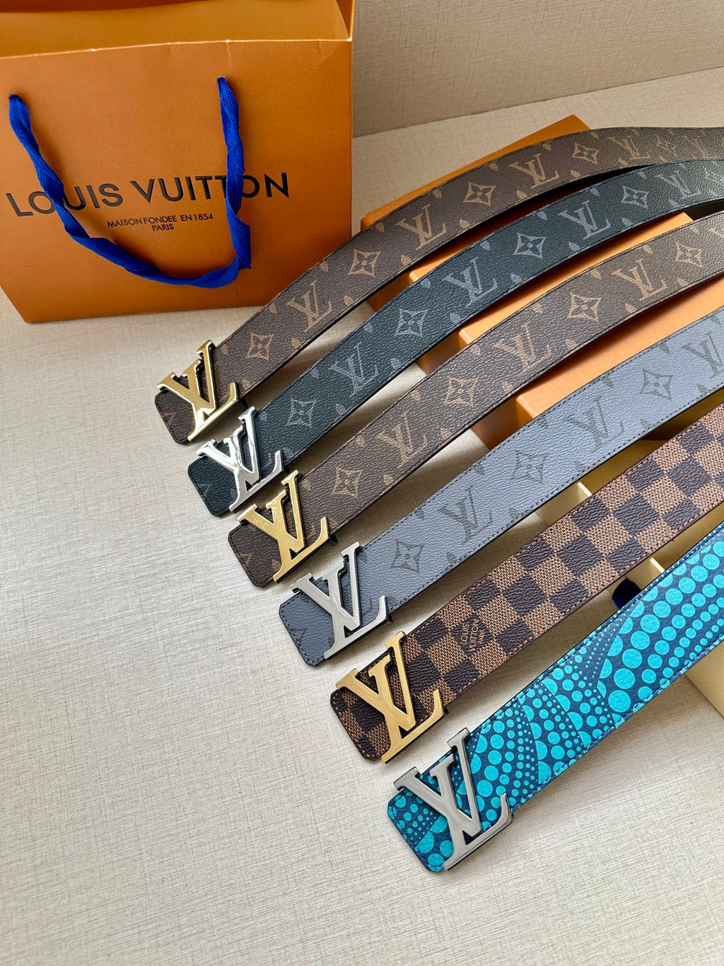 Multiple Louis Vuitton belts with monogram and checkered patterns, gold-tone buckles