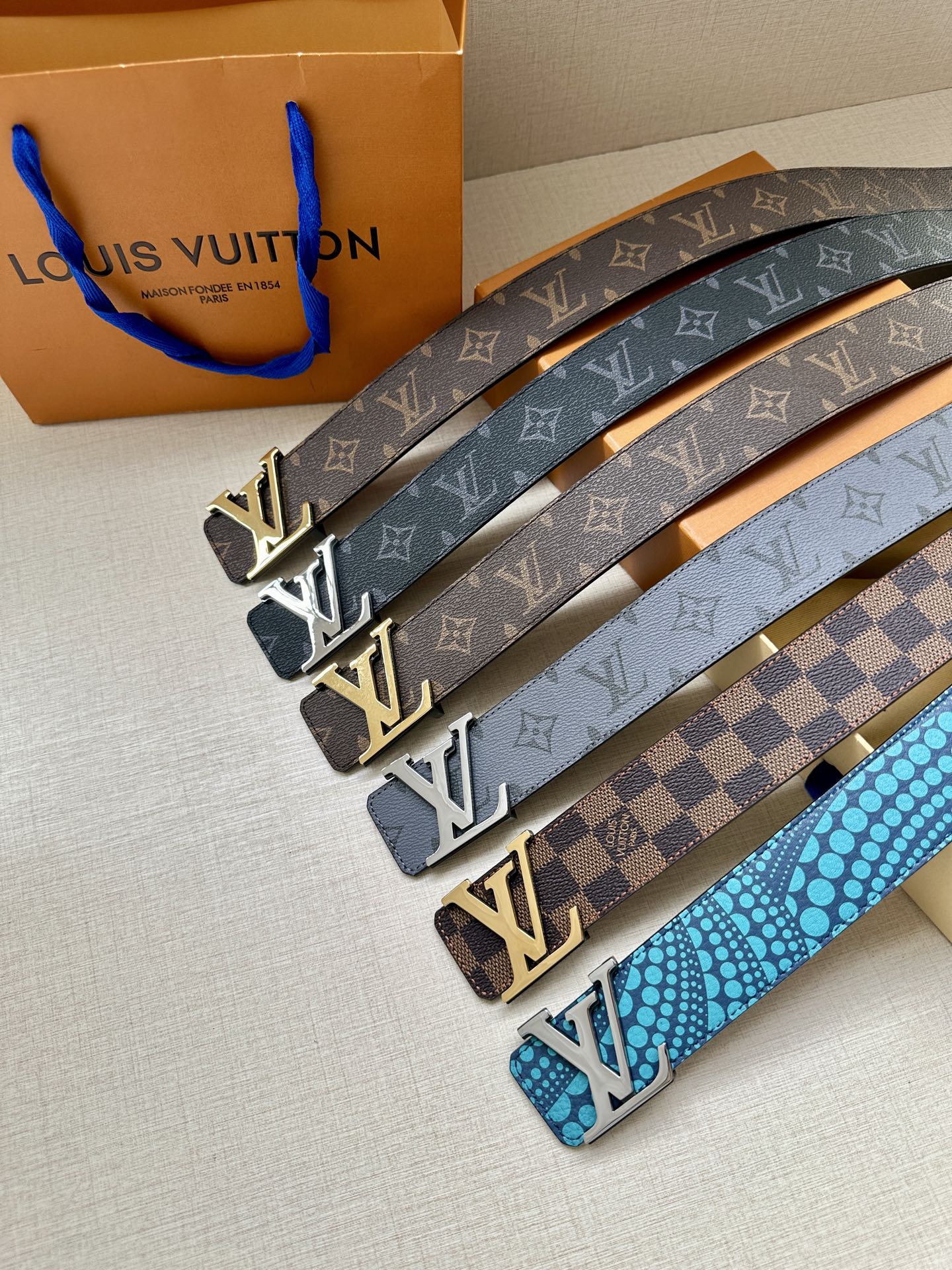 Multiple Louis Vuitton belts with monogram and checkered patterns, gold-tone buckles