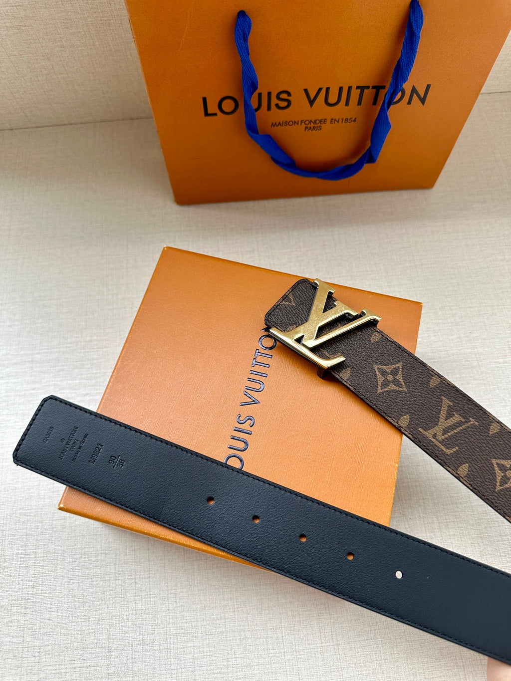 Louis Vuitton monogram belt with gold buckle, dark leather strap and buckle front