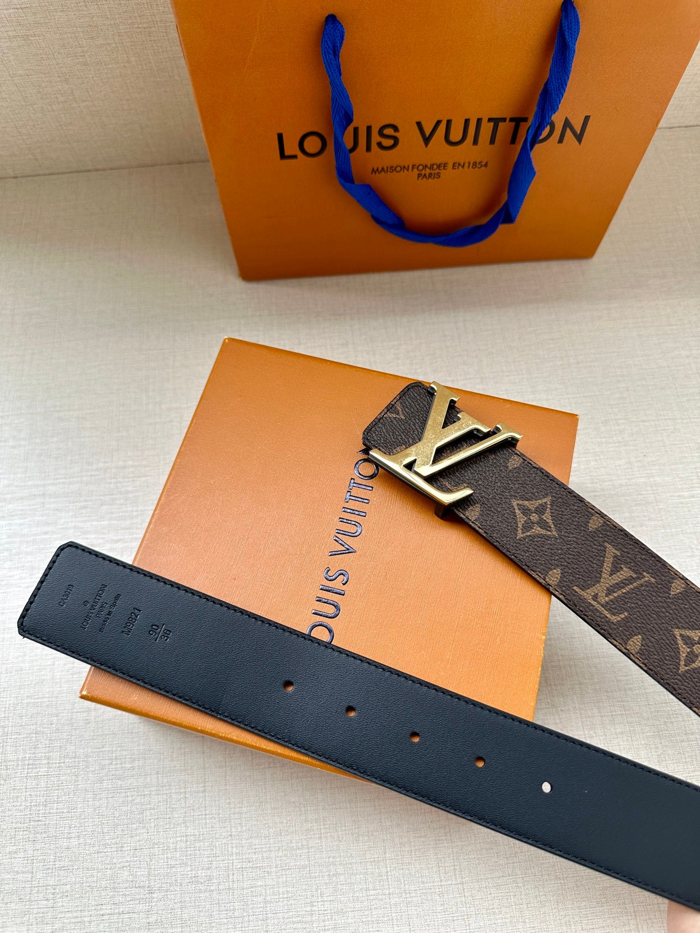 Louis Vuitton monogram belt with gold buckle, dark leather strap and buckle front