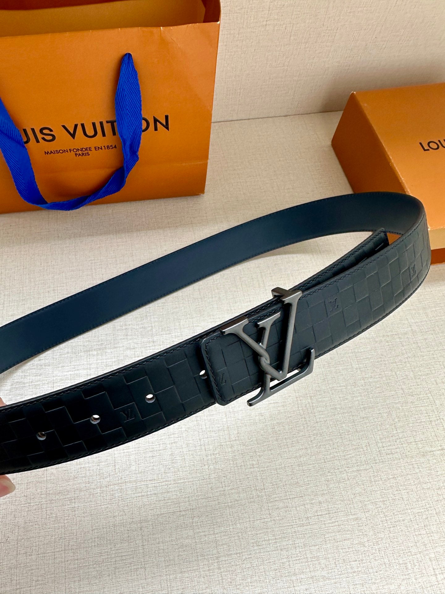 Dark navy belt with rectangular LV buckle and embossed strap