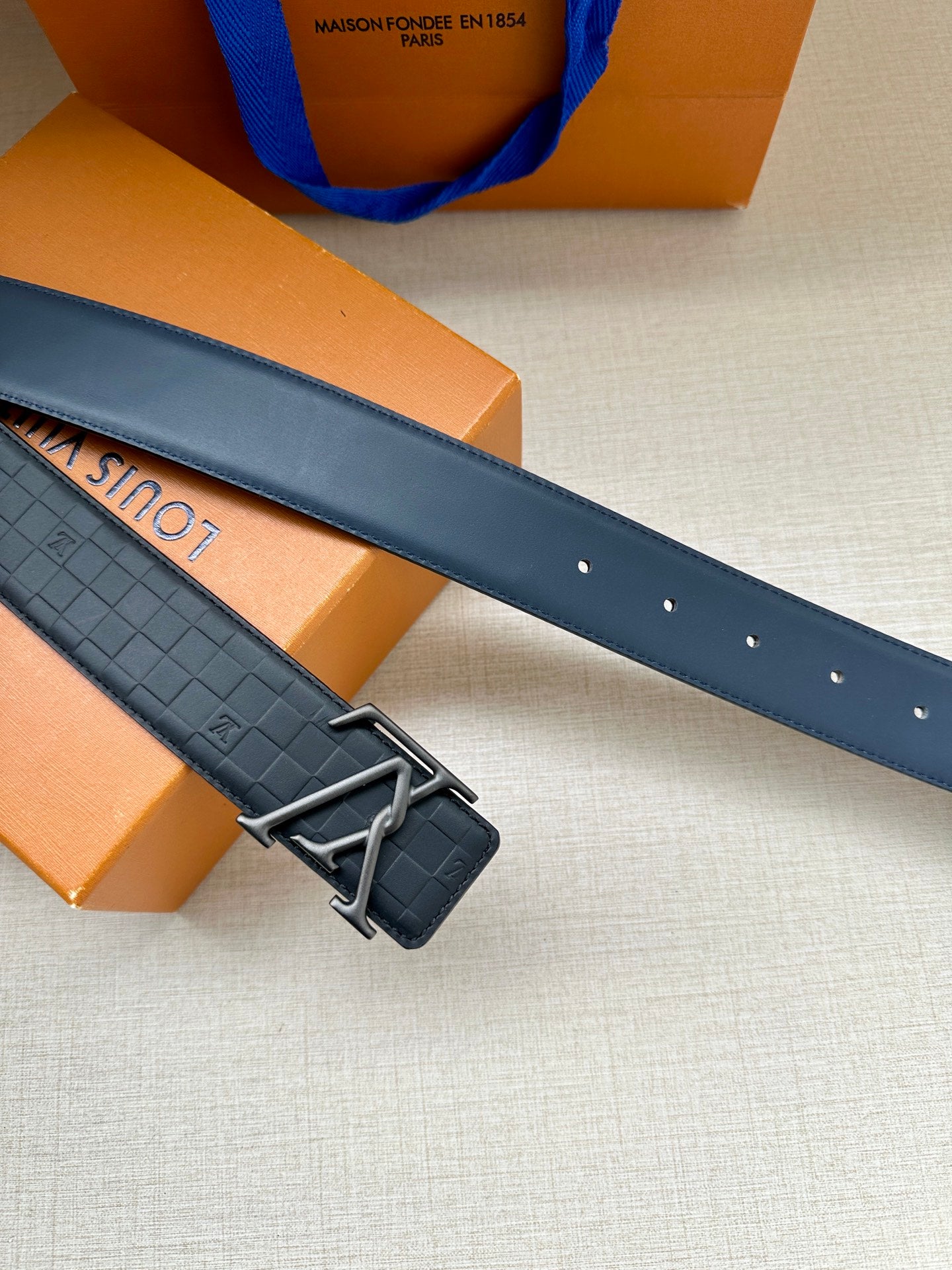 Dark navy belt with embossed pattern, LV buckle, and hole row