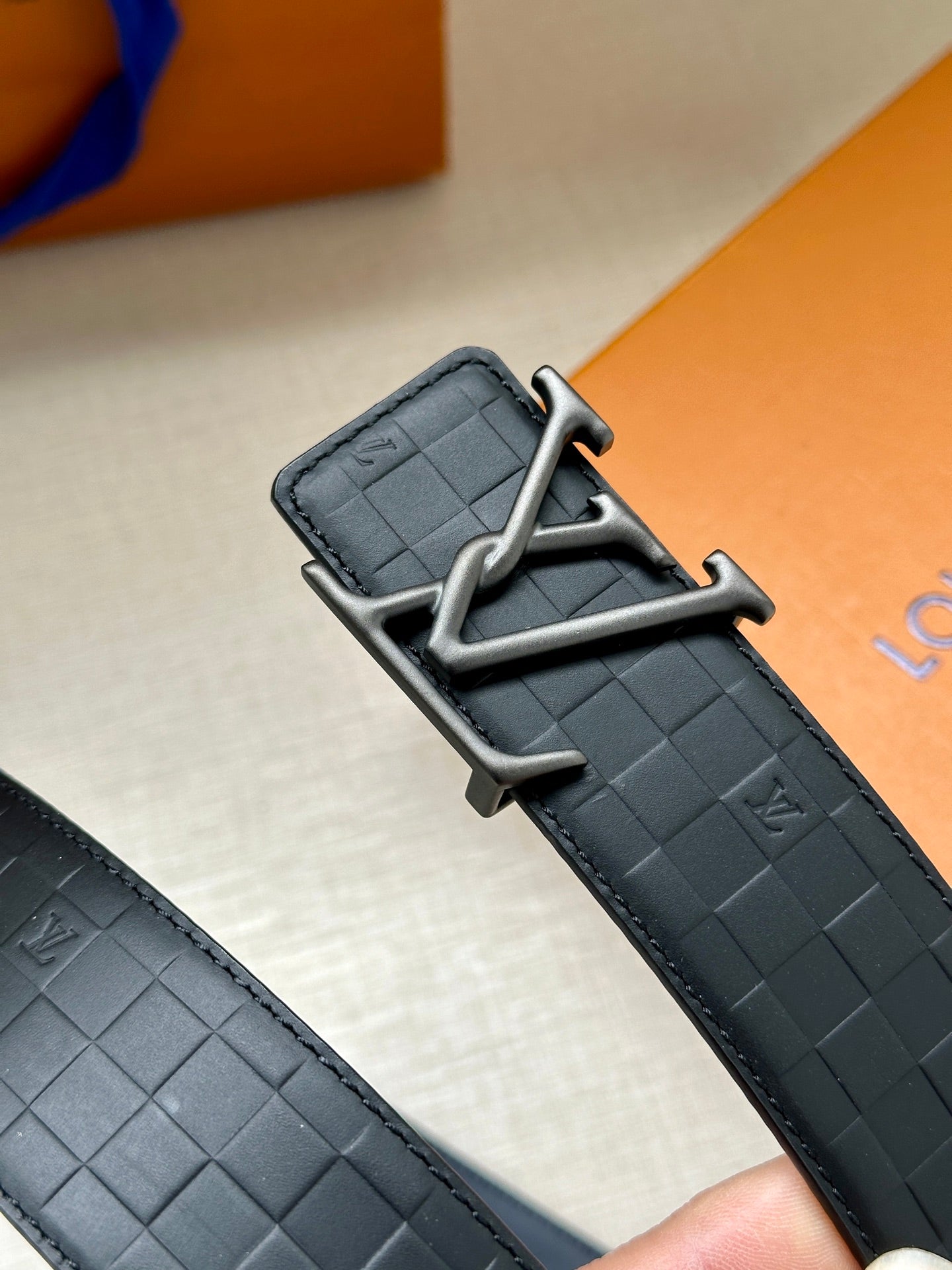 Dark navy belt close-up with LV silver-tone buckle and embossed texture