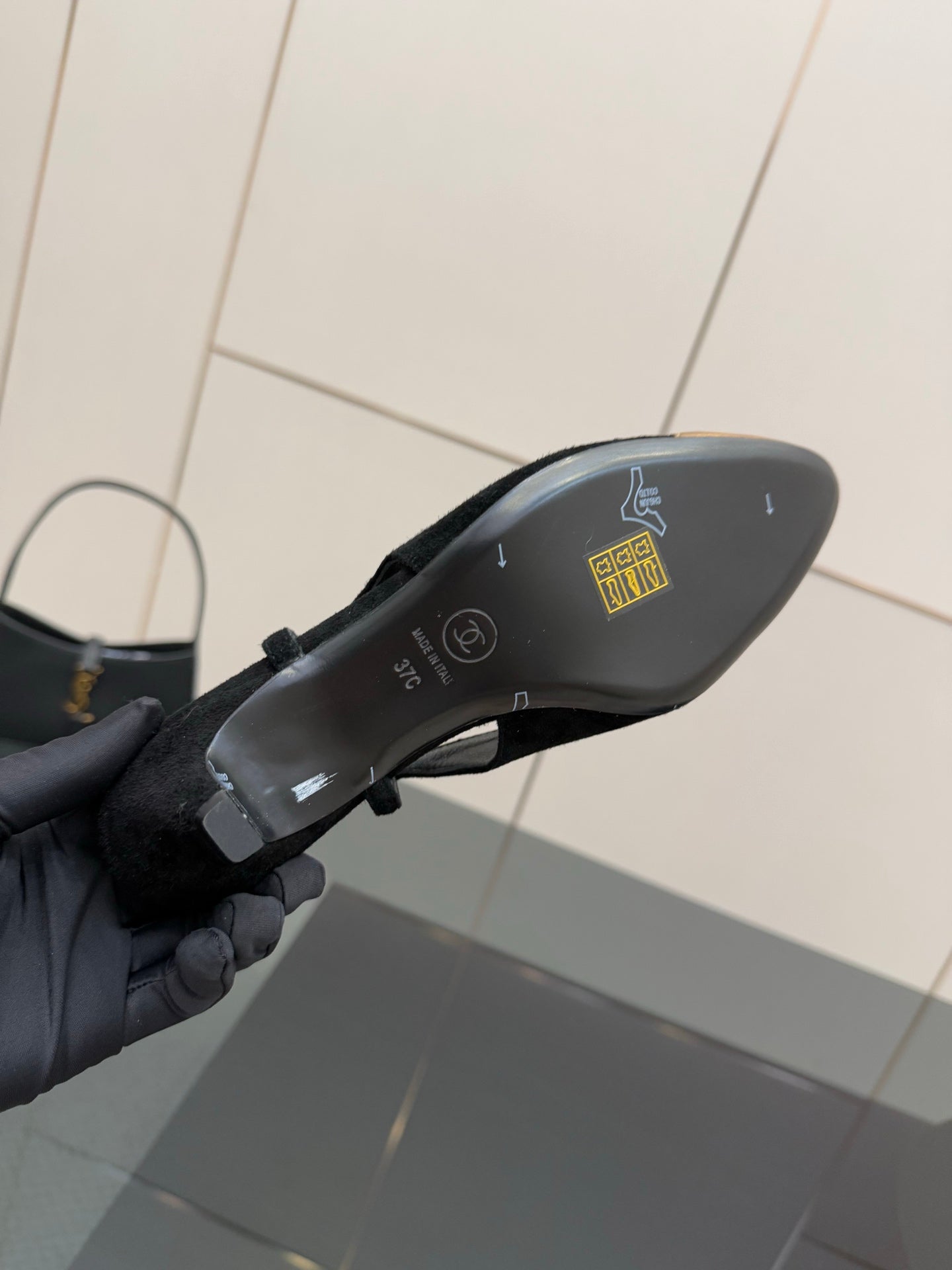 Bottom view of a black ballet flat in hand, with printed details.