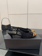Black suede sling-back ballet flat with gold toe cap and bow laces, side view.