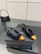 Black suede ballet flats with gold toe caps and bow laces, side view.