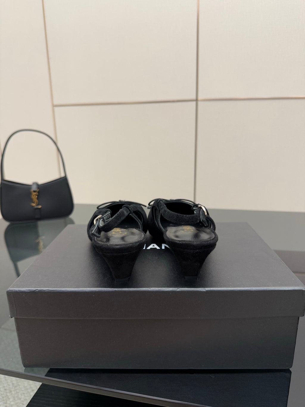 Black ballet flats with gold toe caps and bow laces, front view on a box.