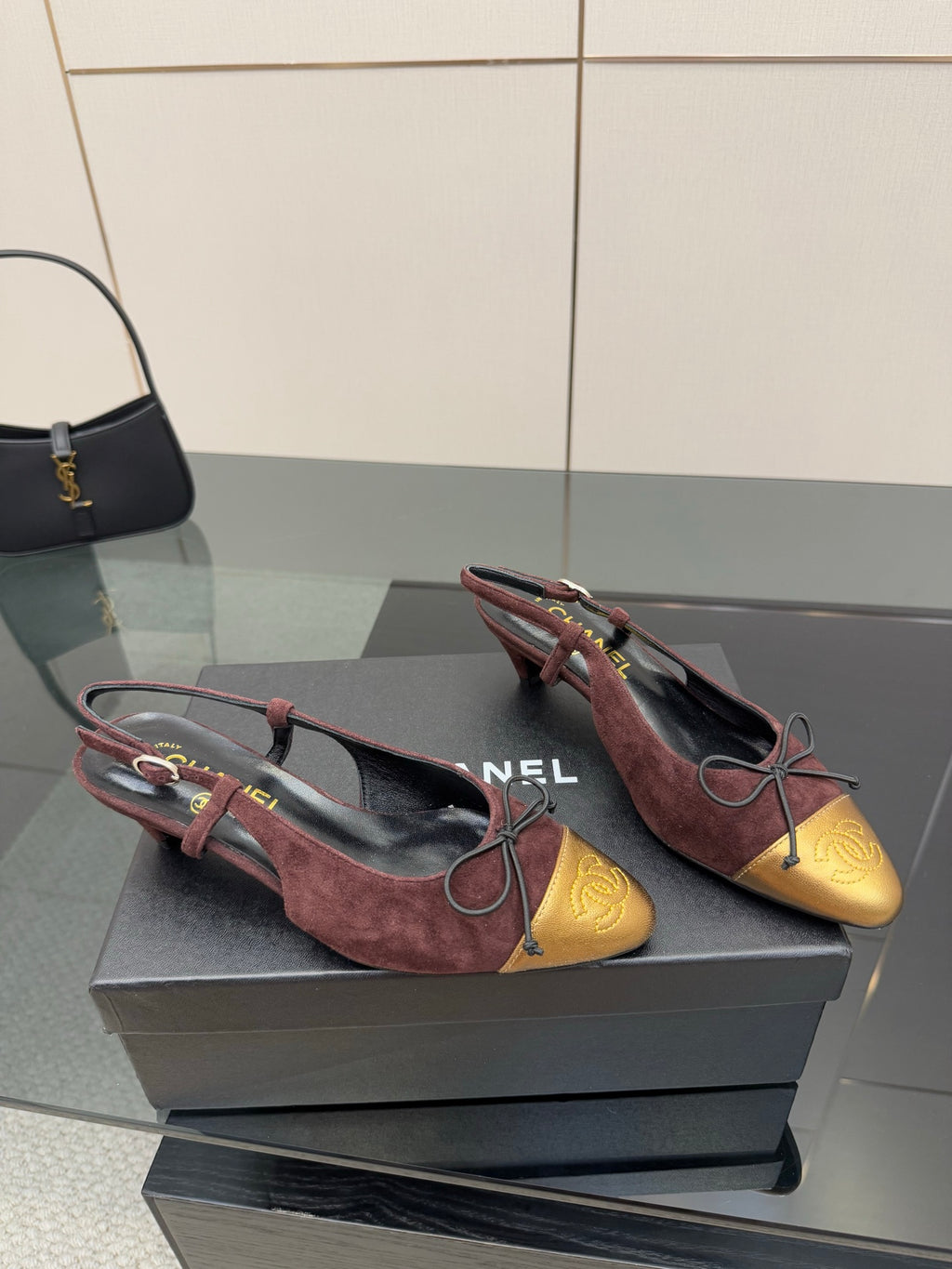 Pair of women’s flats with burgundy suede uppers, gold toe caps, red lace-up bows.