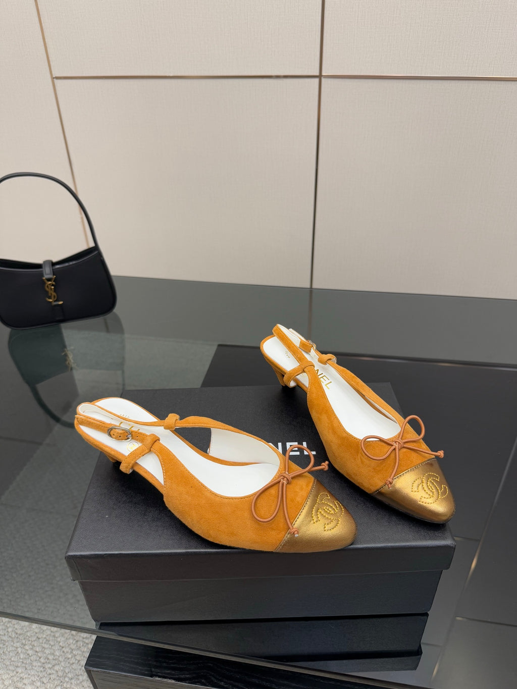 Tan suede flats with lace-up bow front, gold toe embroidery, on display