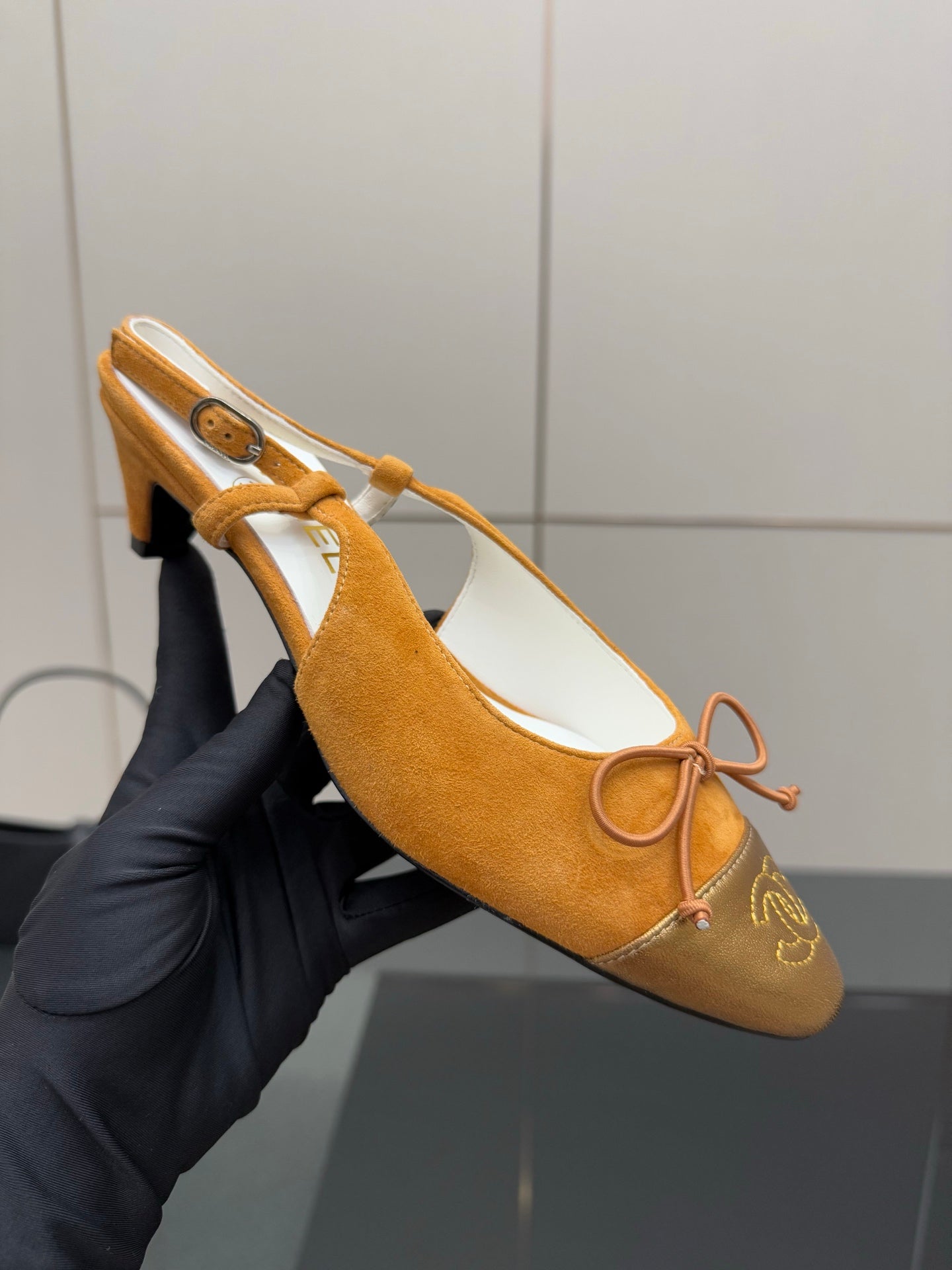 Tan suede slingback heels with lace-up bow strap and gold toe emblem